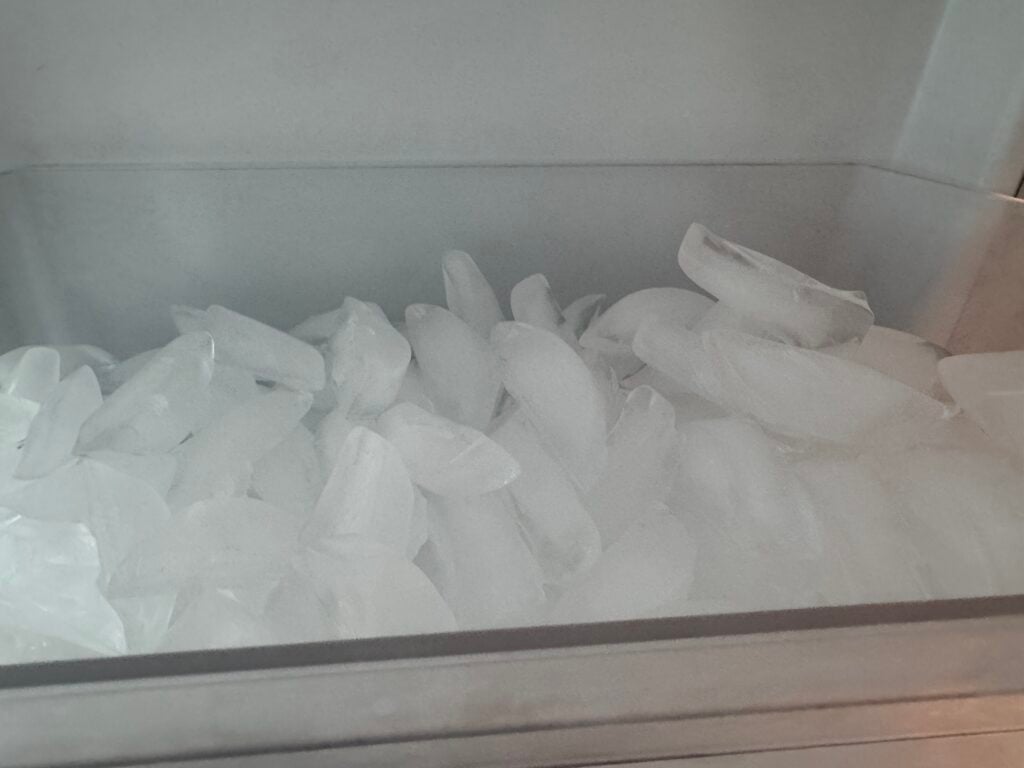 Close-up of ice cubes in a frosty freezer drawer.