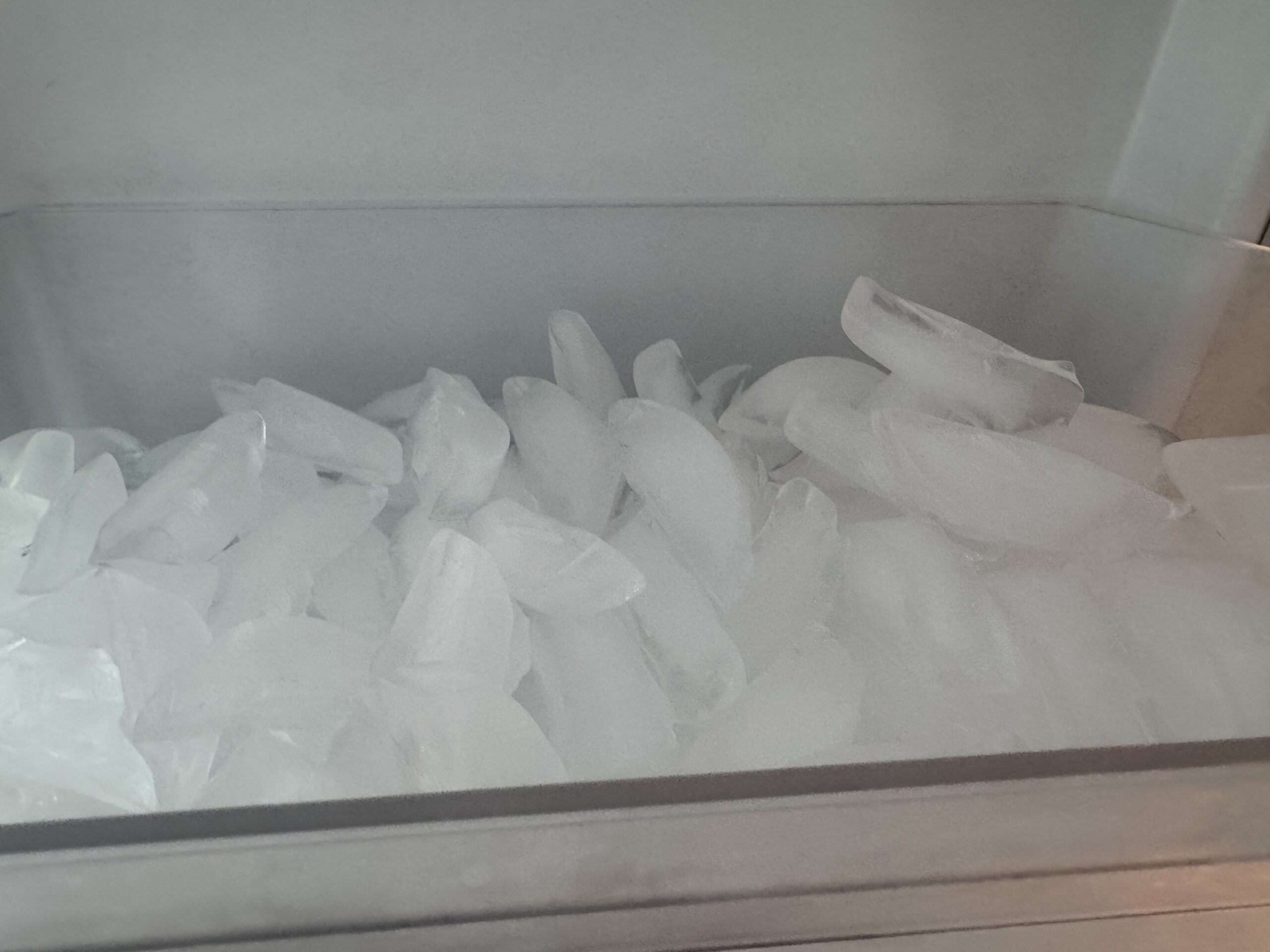 Close-up of ice cubes in a frosty freezer drawer.