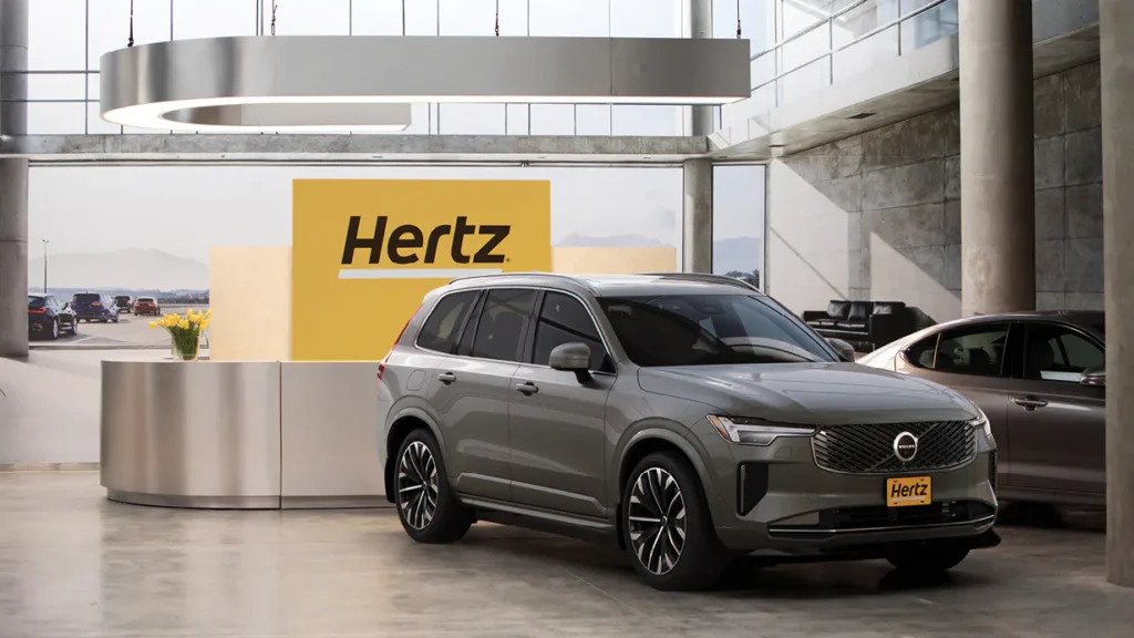 Grey SUV on display inside Hertz showroom with a yellow Hertz sign in the background