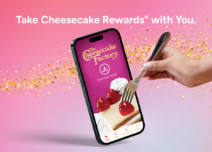 Promotional banner: a smartphone shows The Cheesecake Factory app while a hand holds a fork over a cheesecake slice on a pink gradient background